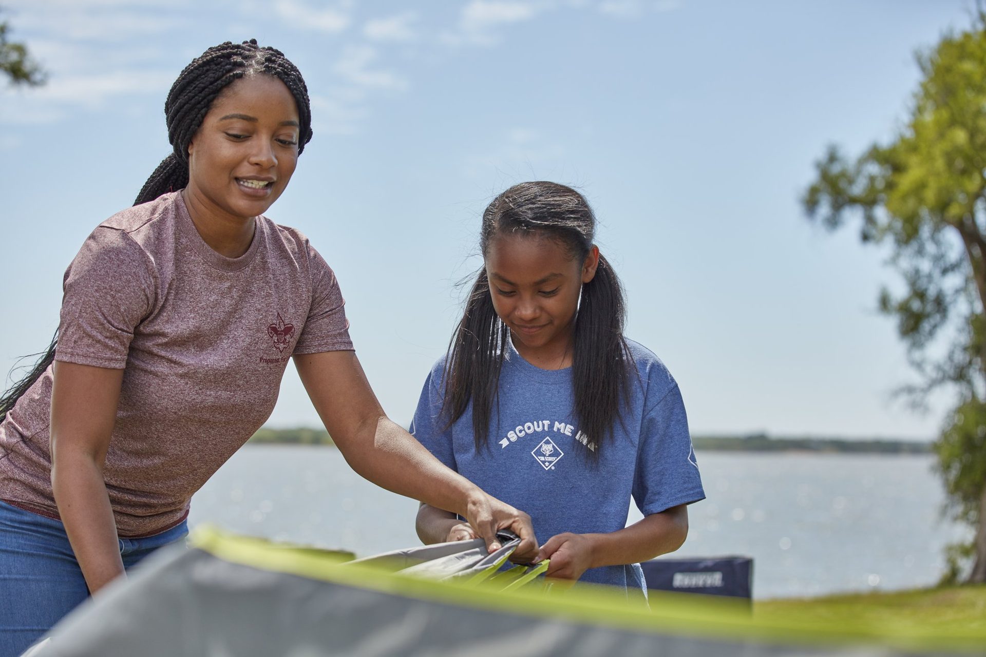 A Scout and leader setting up a tent by the lake